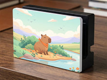 A pastel Switch case with a smiling capybara, green hills, a river, and a soft muted sky.