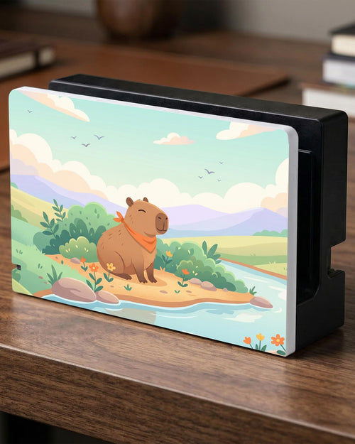 A pastel Switch case with a smiling capybara, green hills, a river, and a soft muted sky.