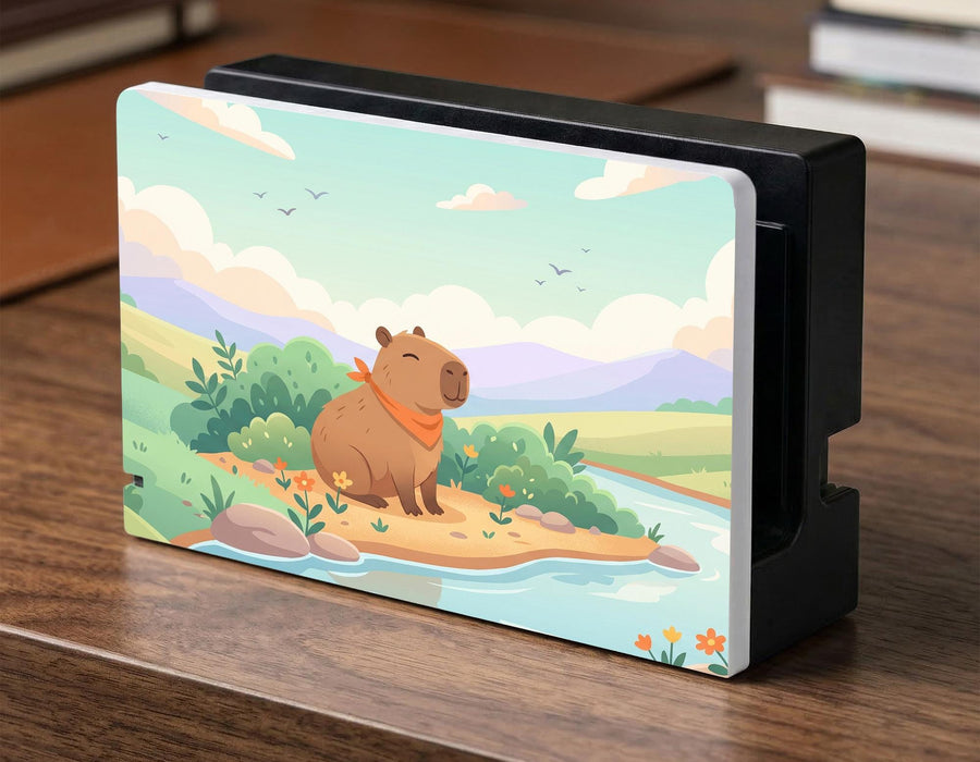 A pastel Switch case with a smiling capybara, green hills, a river, and a soft muted sky.
