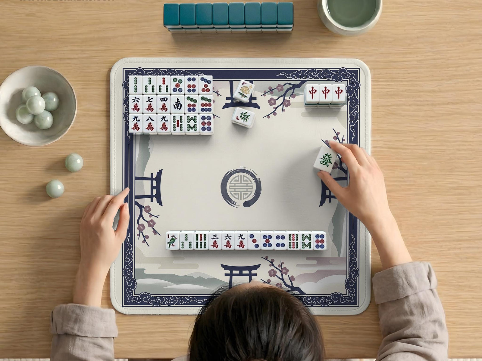 Navy and cream square mahjong mat with cherry blossom branches and a torii gate design, shown as a small tabletop play surface.