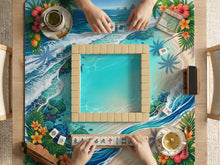 Mahjong table mat with a tropical island shoreline design, blue lagoon water, ocean waves, coral accents, palm leaves, and hibiscus flowers around the edges.