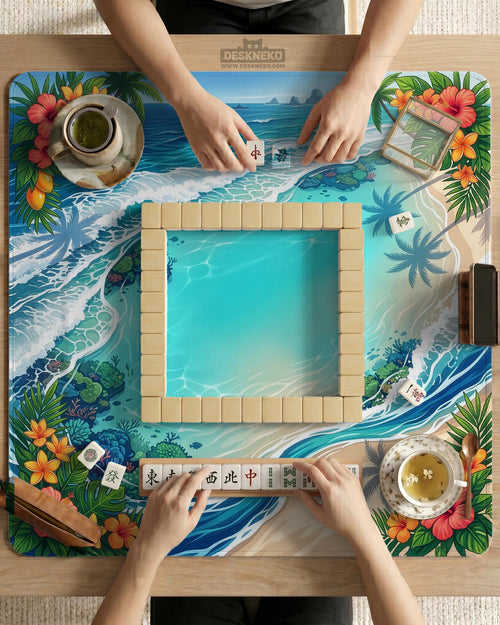 Mahjong table mat with a tropical island shoreline design, blue lagoon water, ocean waves, coral accents, palm leaves, and hibiscus flowers around the edges.