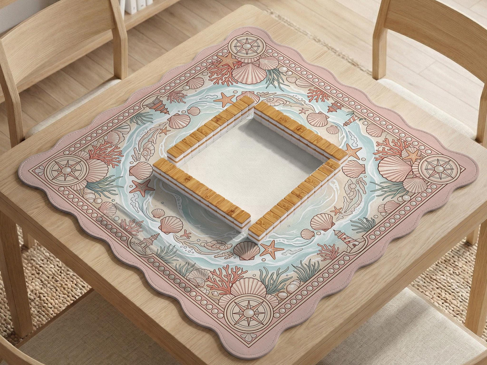 Blush pink mahjong table mat with seashells, coral branches, starfish, and soft seafoam wave details around the border.