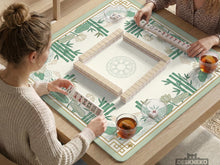 Sage green mahjong mat with bamboo leaves and lotus flowers printed across the surface.
