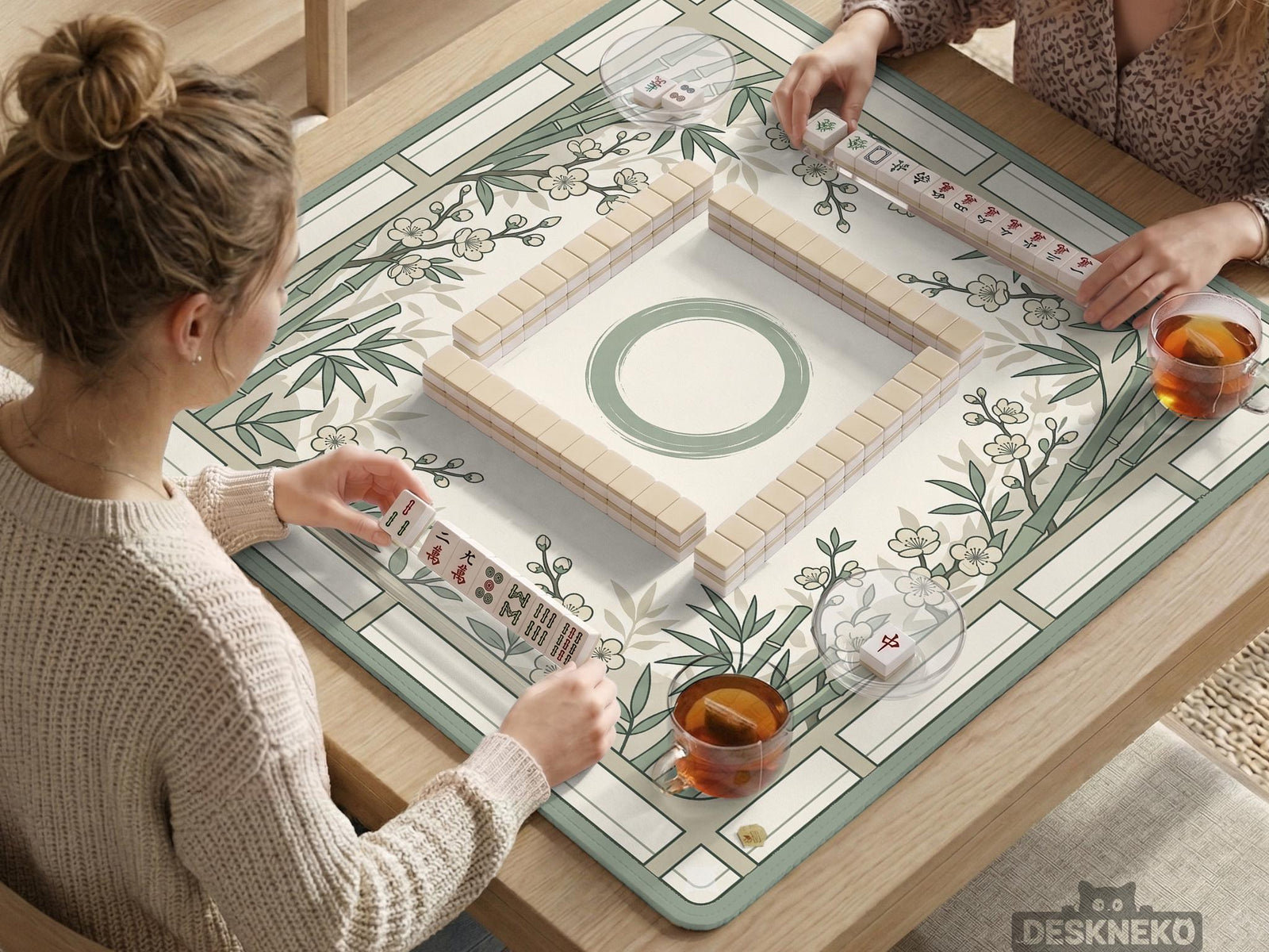 Sage green square mahjong mat with bamboo stalks and cherry blossom branches printed across the surface.