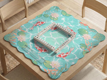 Square mahjong playing mat with aqua background, coral accents, floating lily pads, and koi fish circling the play area.