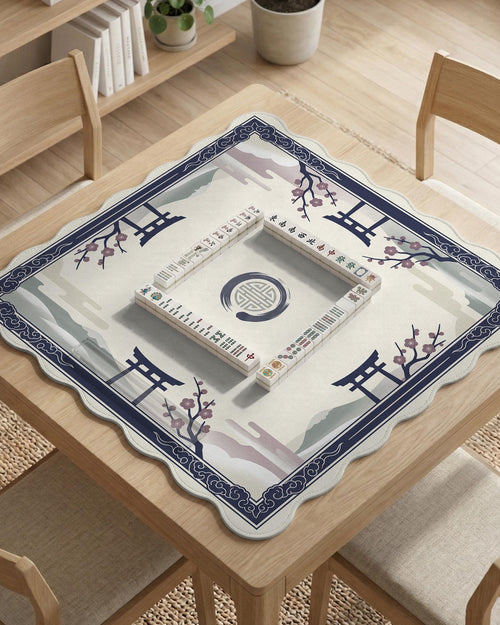 A navy square mahjong mat with a framed center and a sakura and torii design around the edges.