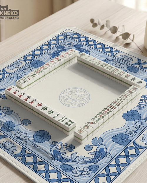 Blue and white square mahjong table mat with koi fish, lotus flowers, water lilies, and flowing wave patterns around a plain center.