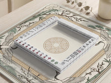 Square mahjong table mat with a cream center and a border design of cranes, bamboo, plum blossoms, and a geometric frame in sage green and warm gold.