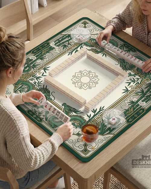 Square mahjong mat with a cream center and a border featuring emerald green dragons, bamboo stalks, cloud shapes, and geometric details.