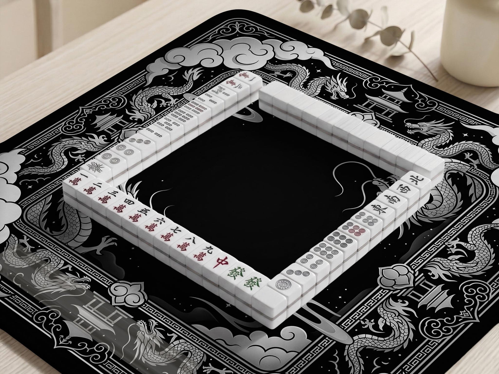 Square black mahjong mat with a dragon illustration in the center and a silver cloud border around the edges.