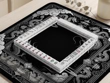 Square black mahjong mat with a dragon illustration in the center and a silver cloud border around the edges.