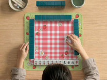 Pink gingham mahjong mat with strawberries, daisies, and sage green border details.