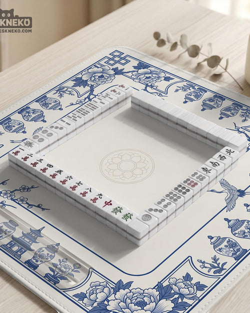 Blue and white mahjong mat with floral peonies, blossom branches, and porcelain jar illustrations around a clean center.