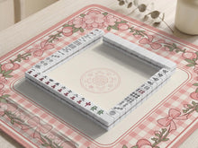 Pink gingham mahjong mat with a floral border, cherry blossom details, and a bow design around a plain center play area.