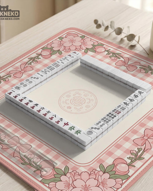 Pink gingham mahjong mat with a floral border, cherry blossom details, and a bow design around a plain center play area.