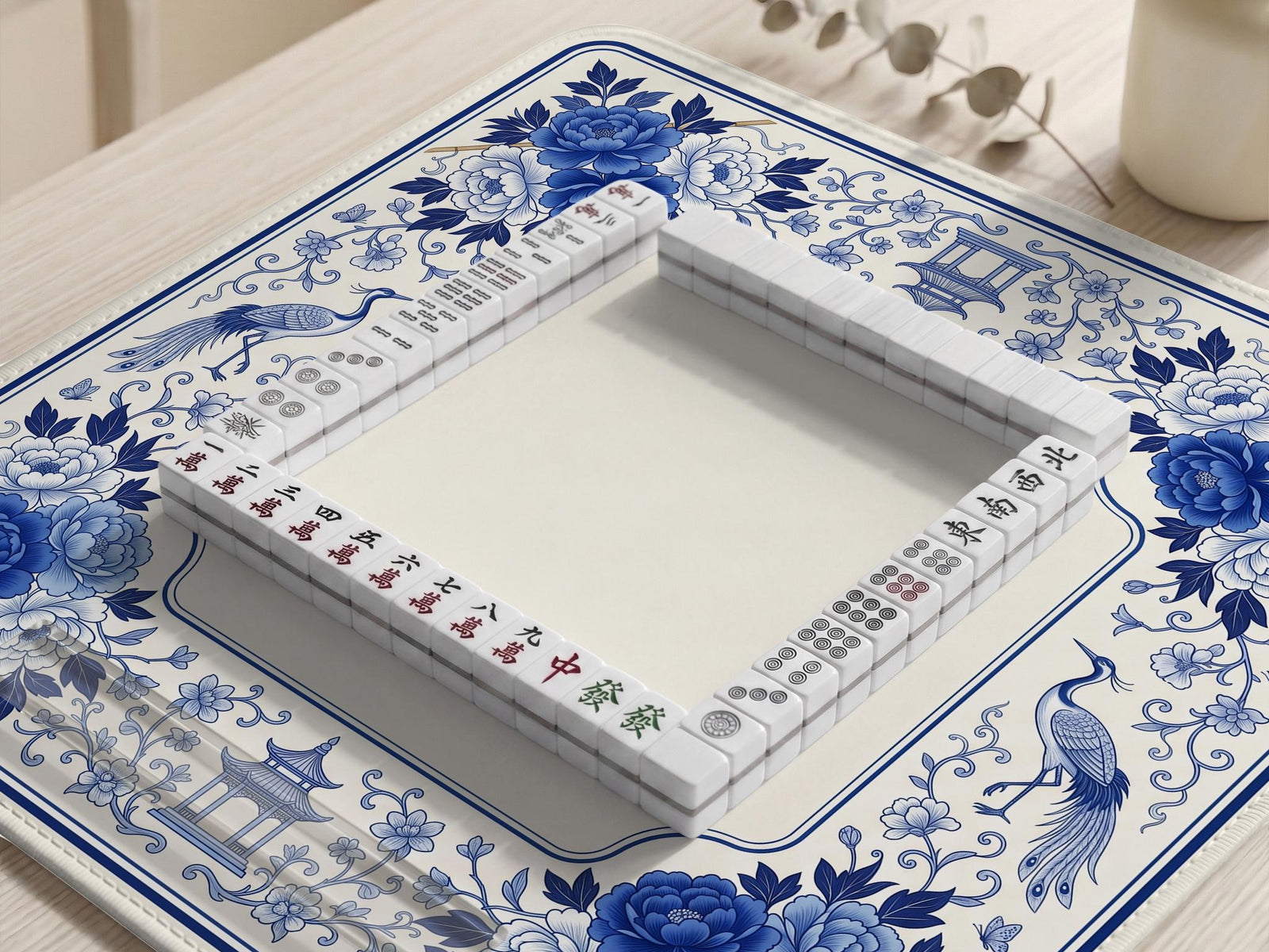Square blue and white mahjong mat with peonies, cranes, pagoda accents, and chinoiserie linework around a plain center.