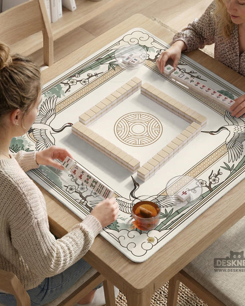 A square cream and sage mahjong mat with a crane, bamboo, blossoms, and a thin gold border.