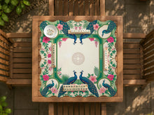 Green mahjong mat with peacocks, hibiscus flowers, tropical leaves, cream center space, and a scalloped floral border.