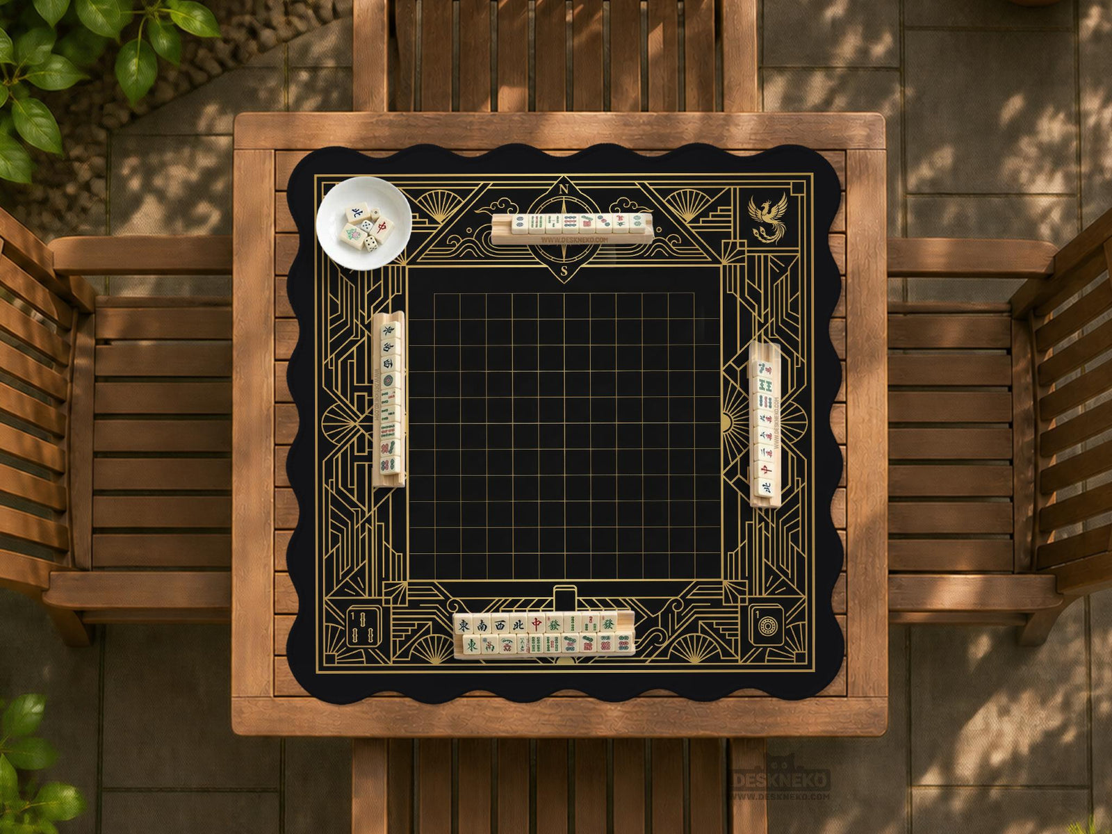 Black and gold square mahjong mat with a scalloped edge, geometric border, thin line details, fan motifs, and dragon and phoenix accents around an open center.
