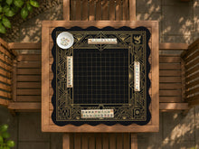 Black and gold square mahjong mat with a scalloped edge, geometric border, thin line details, fan motifs, and dragon and phoenix accents around an open center.