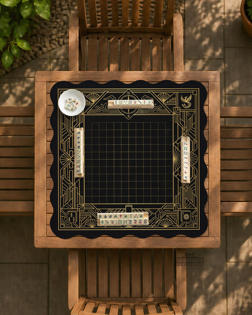Black and gold square mahjong mat with a scalloped edge, geometric border, thin line details, fan motifs, and dragon and phoenix accents around an open center.