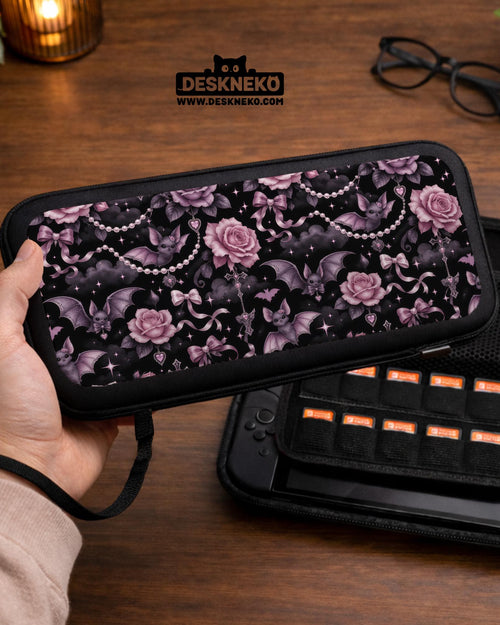 A black Switch carrying case with a pink gothic rose print, small bats, ribbon bows, pearl chain details, and tiny sparkles.