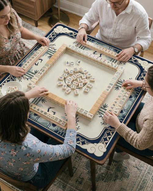 Navy and cream square mahjong mat with cranes, bamboo, clouds, and floral corner details around a plain center area.