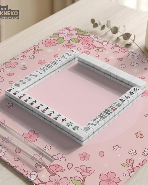 Pink mahjong mat with cherry blossom flowers, scattered petals, and a floral frame on a pastel background.