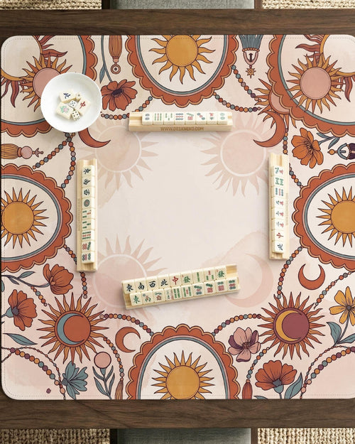A square terracotta mahjong mat with suns, crescent moons, and floral accents around a patterned border and open center.