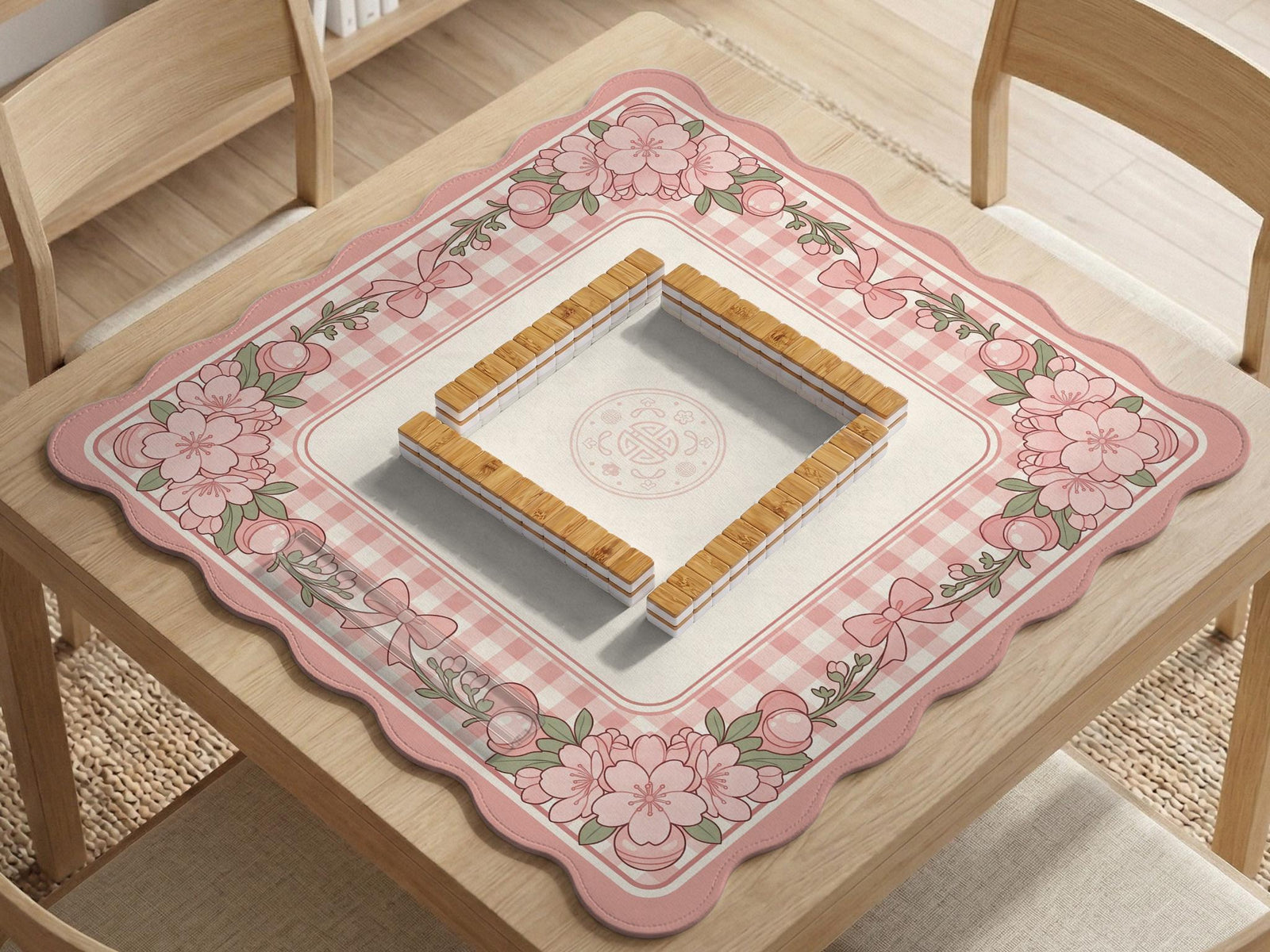 Square pink mahjong mat with a gingham border, floral corner details, and ribbon accents on a light background.