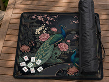 Square black mahjong mat with a gold peacock, blush flowers, dark botanical details, and a gold border.