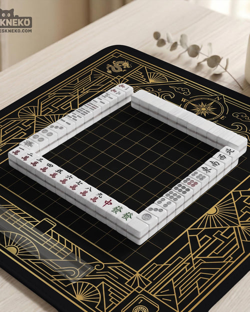 Black mahjong mat with a gold geometric Art Deco border, fan shapes, compass-style details, dragon and phoenix elements, and a plain center play area.