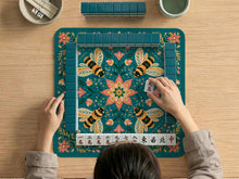 Green mahjong mat with a botanical bee and floral mandala design in teal, coral, cream, and gold.