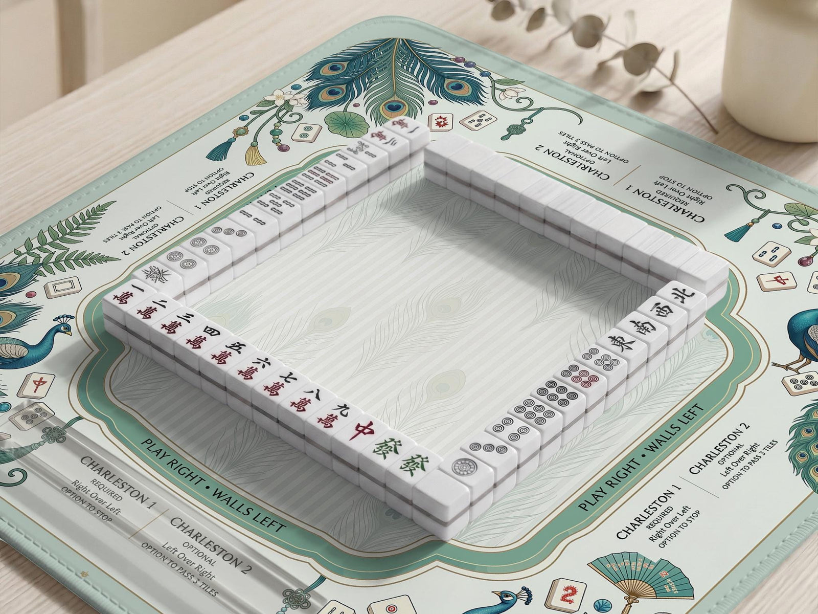 Mint green mahjong mat with peacock feather artwork, framed rule text around the edges, and a clear center play area.