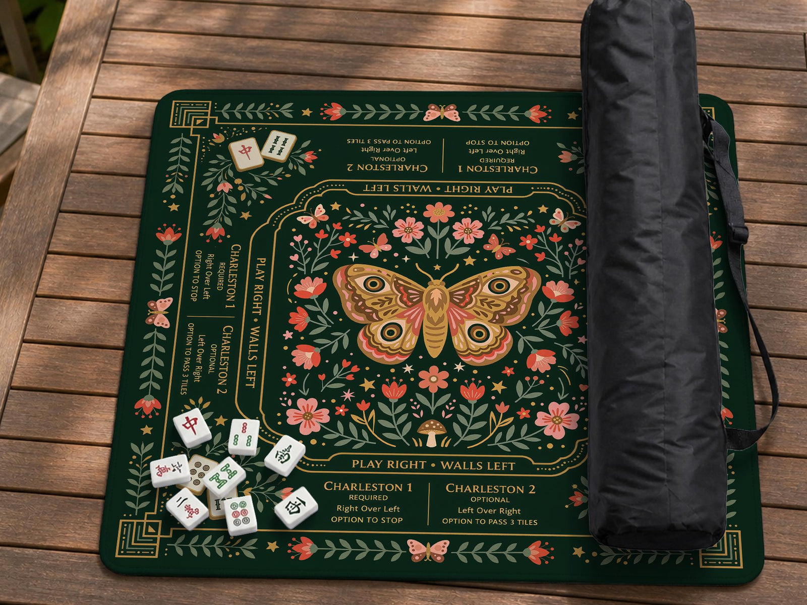 Dark botanical mahjong table mat with a floral border, large moth and butterfly design in the center, gold corner frame, and printed rules layout around the edge.