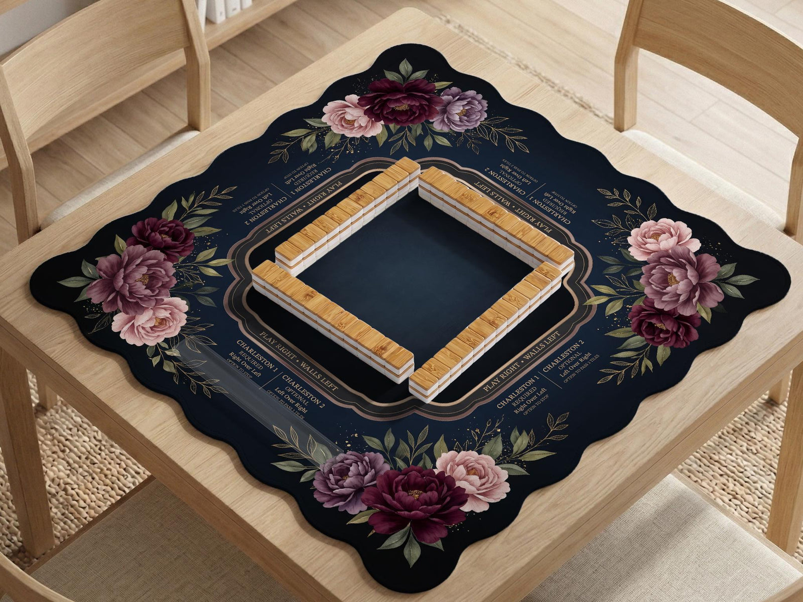 Burgundy mahjong mat with a floral border, gold botanical details, and printed American Mahjong rules on a dark background.