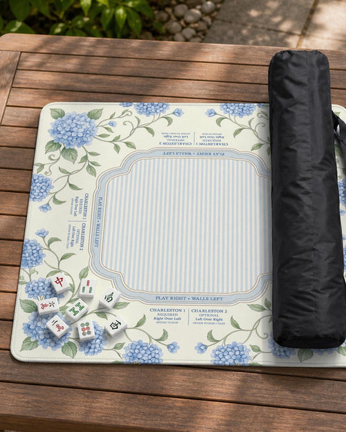 Blue hydrangea floral mahjong mat with a cream background, sage green vines, a striped center, and printed rule notes around the border.