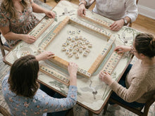 Sage green square mahjong mat with a chinoiserie design featuring cranes, bamboo, blossoms, and mountains, with rules printed around the border.