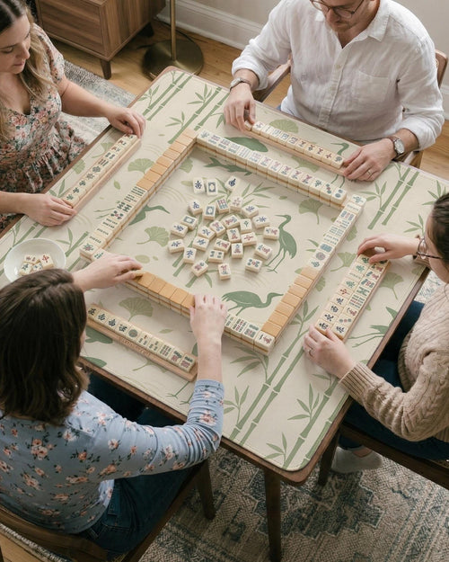 Sage green mahjong mat with a bamboo garden design, koi fish, crane birds, ginkgo leaves, and a cream background.