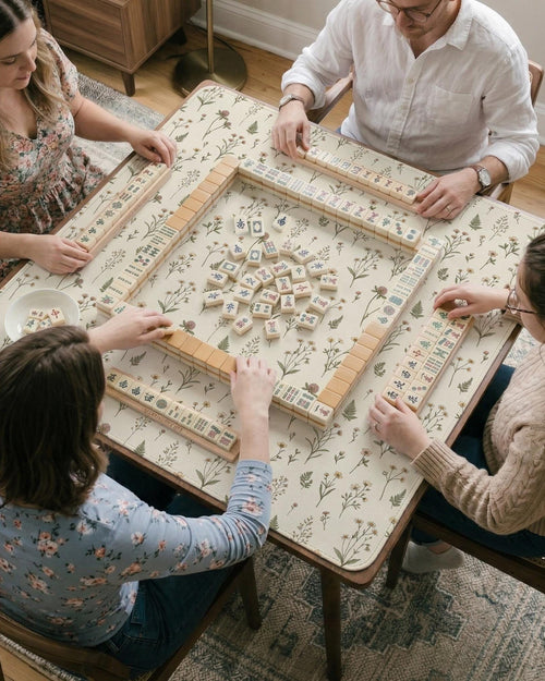 Cream mahjong mat with a delicate meadow flower pattern, soft beige background, and muted sage green leaves.