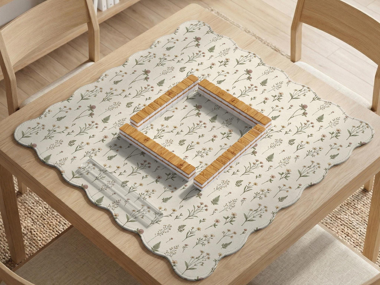 Cream mahjong mat with a floral pattern of small wildflowers and sage leaves, shown with a scalloped edge on a light neutral background.