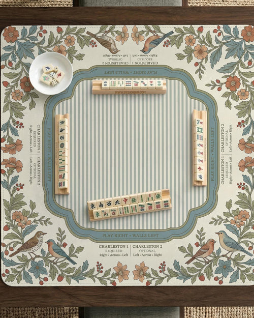 Square mahjong mat with a cream background, blue birds, sage leaves, terracotta flowers, and a decorative botanical border with printed rules text.