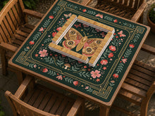 Dark green square mahjong mat with floral branches, small red blossoms, gold line details, and a large moth in the center.