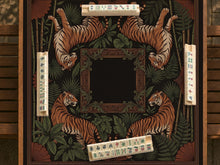 Black square mahjong mat with mirrored tiger faces, bamboo, dark tropical leaves, ornate border details, and orange accents.