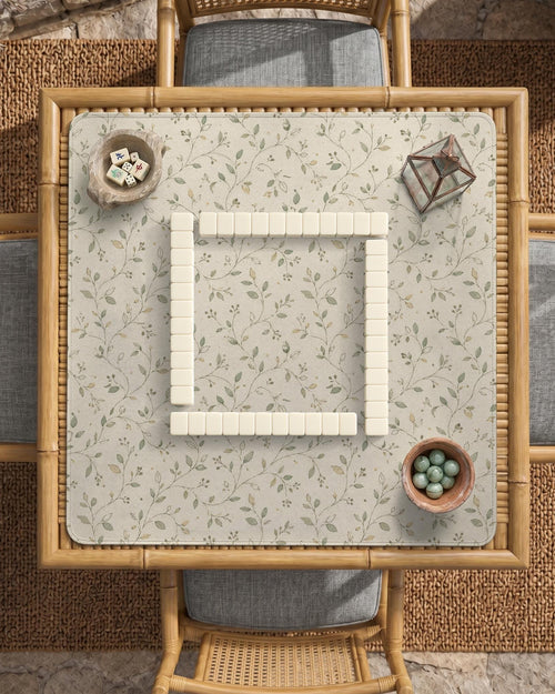 Sage green botanical mahjong mat with a cream background, trailing vines, and muted leaf designs.
