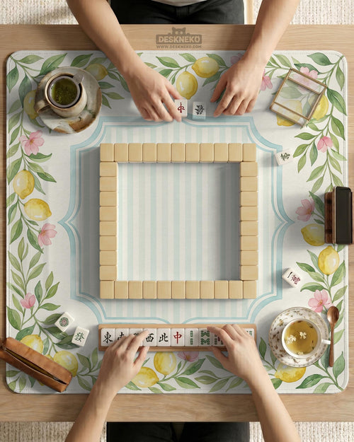 Square pastel yellow mahjong mat with lemon branches, small pink flowers, a striped center, and a light aqua border.