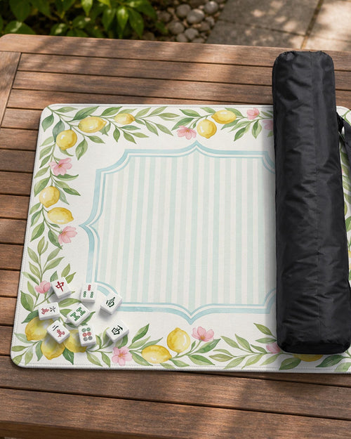 Square yellow mahjong mat with a citrus garden border, green vines, pink blossoms, aqua accents, and a plain center play area.