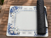 Blue and white mahjong mat with lucky cats, peonies, hydrangeas, small tiles, and gold accents on a decorative tabletop background.