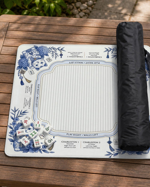 Blue and white mahjong mat with lucky cats, peonies, hydrangeas, small tiles, and gold accents on a decorative tabletop background.